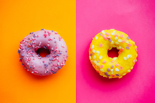 Two sugar glazed donuts on colorful background. - Photo, Image