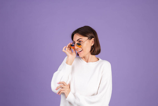 Nuori brunette valkoinen rento villapaita eristetty violetti tausta aurinkolasit onnellinen tyylikäs positiivinen hymyilevä - Valokuva, kuva