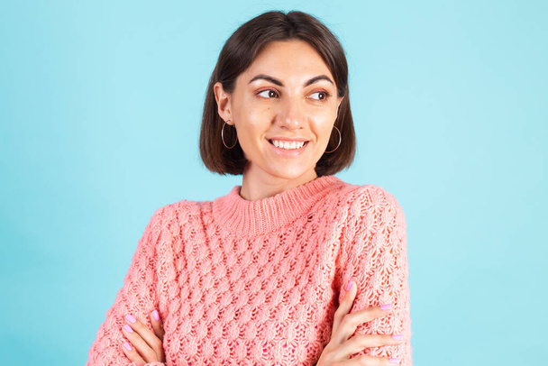 Молода брюнетка в рожевому светрі ізольована на синьому фоні з схрещеними руками посмішка дивитися на камеру ізольовані копії простору
 - Фото, зображення