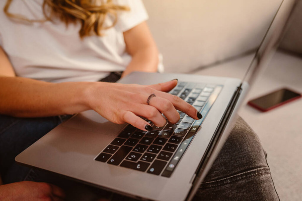 Close-up van een vrouwelijke vinger op laptop toetsenbord thuis. Bedrijfsleven, thuiswerken, online studeren. - Foto, afbeelding