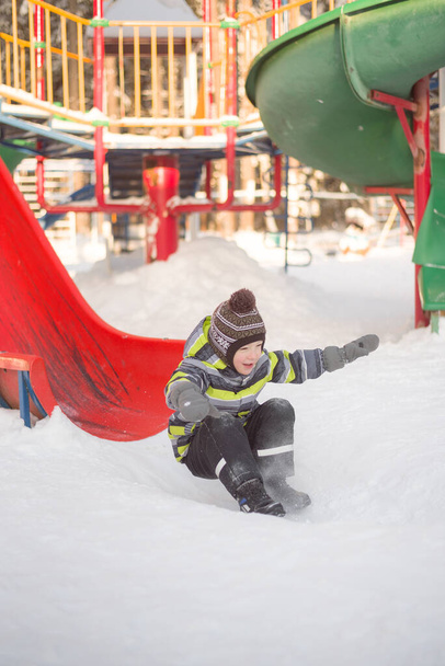 dziecko jeździ na zjeżdżalni i bawi się na placu zabaw w zimie - Zdjęcie, obraz