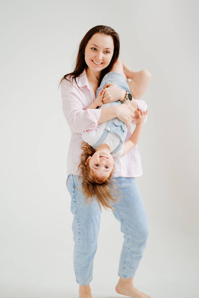 beautiful happy family at photo shoot in white photo studio. Mom and daughter - Zdjęcie, obraz