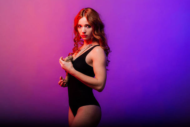Beautiful young redhead woman with snake with a fashionable perfect makeup. Studio shot, neon light - Photo, Image