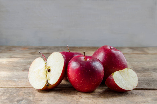 Una composición de manzanas rojas, cortadas y enteras, sobre un fondo claro y vintage. La mitad y cuarto de la fruta. Frutas naturales. - Foto, imagen