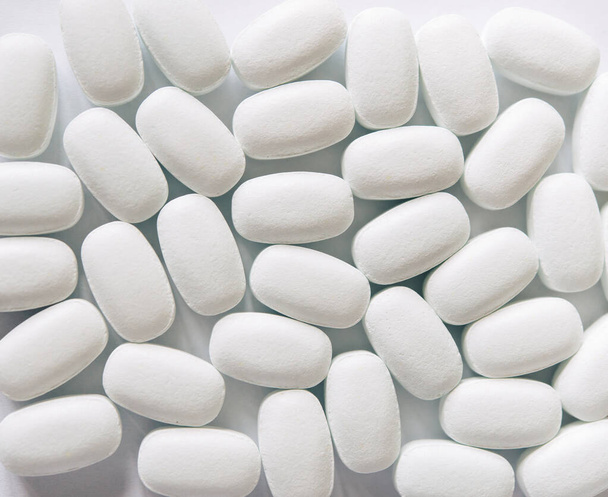 White pills on a white background. Oval white pills close up. Healthcare and medicine. - Photo, Image