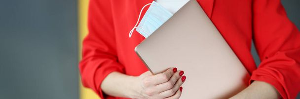 Frau im roten Anzug hält Laptop mit Schutzmasken in Großaufnahme - Foto, Bild