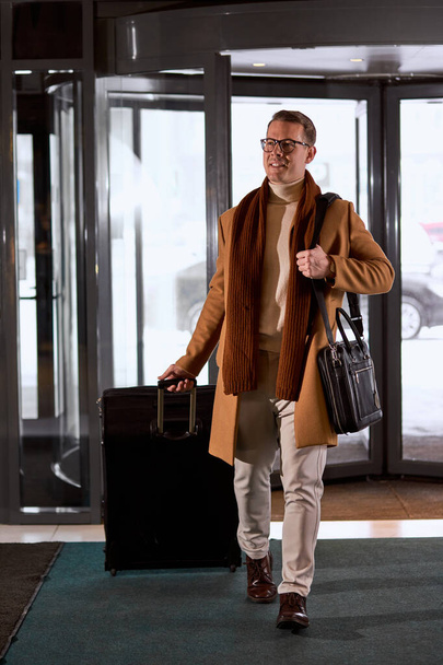 Young excited caucasian business male entering lobby of hotel - 写真・画像