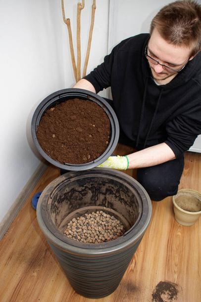 The ground is poured into a decorative flower pot. Soil for palm trees. Plant transplant concept. - Photo, Image