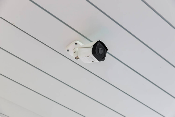 Online Security CCTV camera surveillance system outdoor of house. A blurred night city scape background. Real time Modern CCTV camera on a wall. Equipment system service for safety life or asset. - 写真・画像