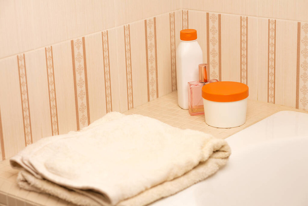 Champú, manteca corporal, aceite para el cabello y toalla de baño en un baño. Espacio para texto - Foto, imagen