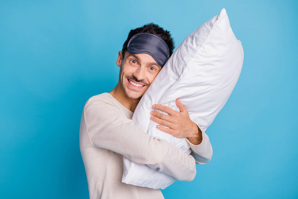 Portrait of nice cheerful funny guy enjoying embracing lying on soft pillow isolated over bright blue color background - Photo, image