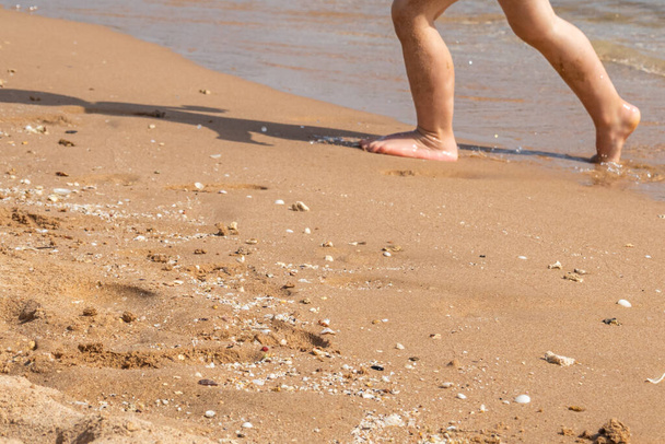 Gyermekláb a homokon a tengerparton - Fotó, kép