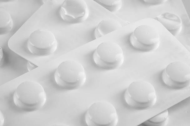 Witte pillen in witte blister op witte achtergrond - Foto, afbeelding