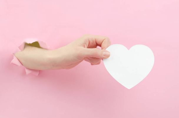 Καρδιά κομμένη από λευκό χαρτί σε γυναικείο χέρι. Χάρτινη καρδιά με χώρο για κείμενο - Φωτογραφία, εικόνα