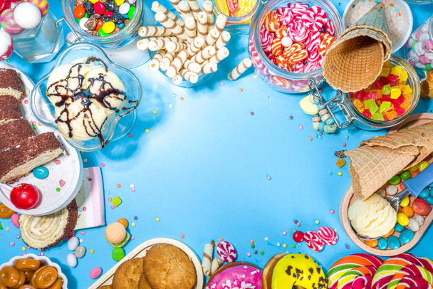 Selection of colorful sweets. Set of various candies, chocolates, donuts, cookies, lollipops, ice cream top view on trendy bright blue sunny background - Photo, Image