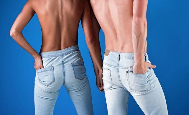 Couple in jeans, back view denim pants, naked sexy couple on blue background. - Foto, afbeelding