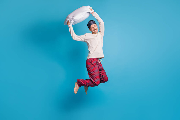 Photo portrait full body view of smiling guy ready for pillow fight jumping up isolated on vivid blue colored background - Foto, afbeelding