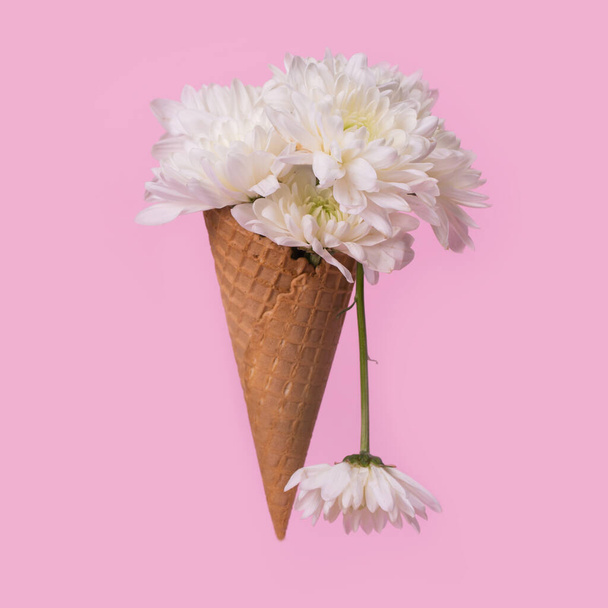 Ice cream cone with white flowers and dripping effect on a pastel pink background. Minimal spring or summer concept. A modern fun concept of gifts, anniversary and love. - Photo, Image