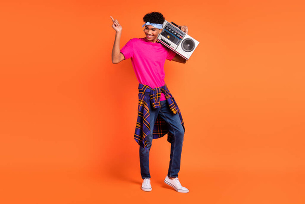 Full body photo of charming young dark skin man hold boombox wear shirt on waist isolated on orange color background - Φωτογραφία, εικόνα