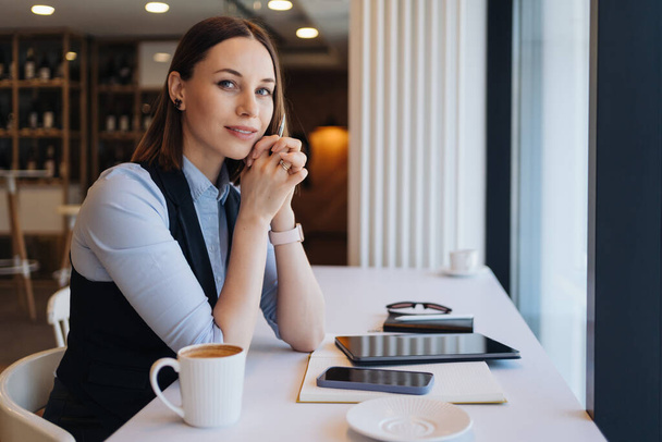 Thoughtful female sitting in cafeteria with a coffee while working - Foto, immagini