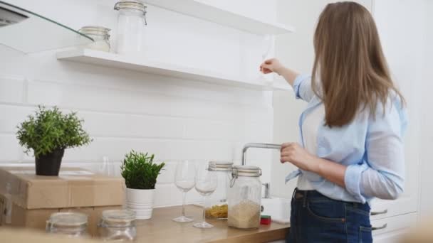 Mulher arranja utensílios de cozinha depois de se mudar para novo apartamento. - Filmagem, Vídeo