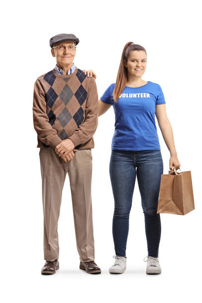Young female volunteer helping an elderly man and carrying a bag isolated on white background - Foto, afbeelding