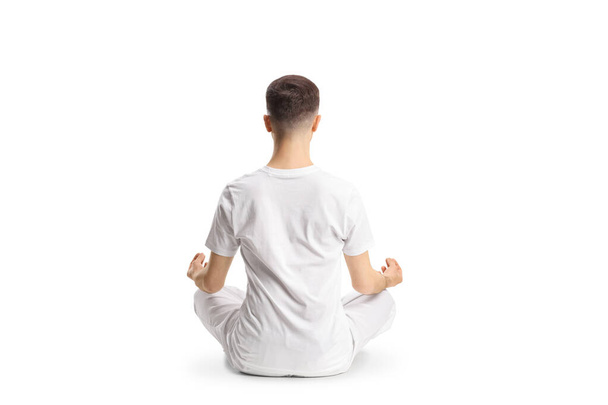 Rear view shot of a man in white clothes sitting and practicing yoga isolated on white background - Fotó, kép