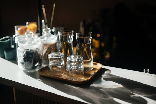 Four glass cups on the bar counter with serving accessories. - Zdjęcie, obraz