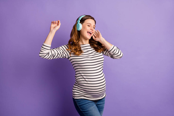 Photo portrait of pregnant carefree woman listening to music in blue headphones isolated on vivid violet colored background - Φωτογραφία, εικόνα