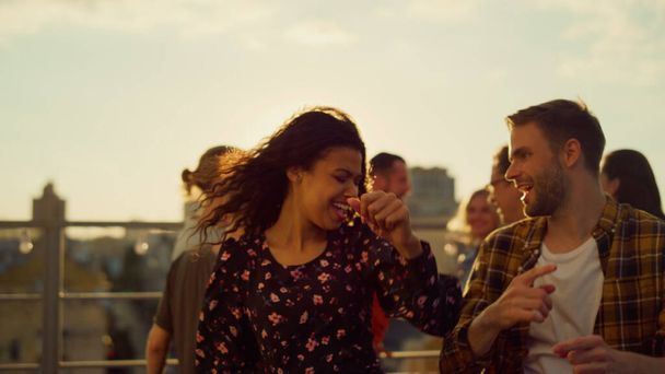 Joyful couple rocking at rooftop disco. Multiracial people dancing at party. - Foto, immagini