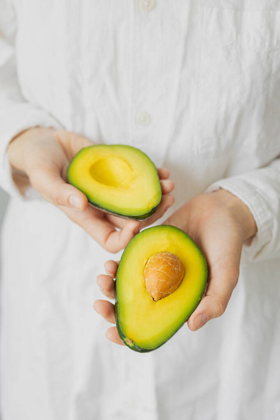 womens hands holding avocado, Caucasian woman in t-shirt - Photo, image