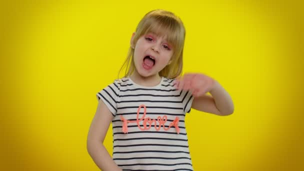 Niña adolescente rubia pequeña niña en camiseta gritando hola, saludando de la mano, dando la bienvenida con gesto de hola - Imágenes, Vídeo