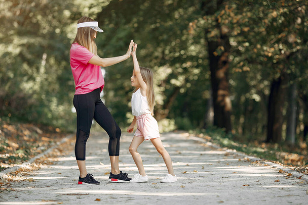 Mother with daughter doing sport in a summer park - Photo, Image