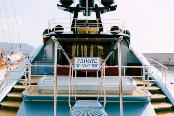 Stern trawl of a beautiful motor white yacht with a wooden ladder. Inscription: PRIVATE No Boarding. Close-up - Photo, Image