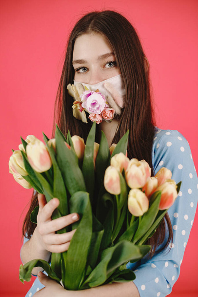Girl in a mask with flowers on a red background - Foto, imagen