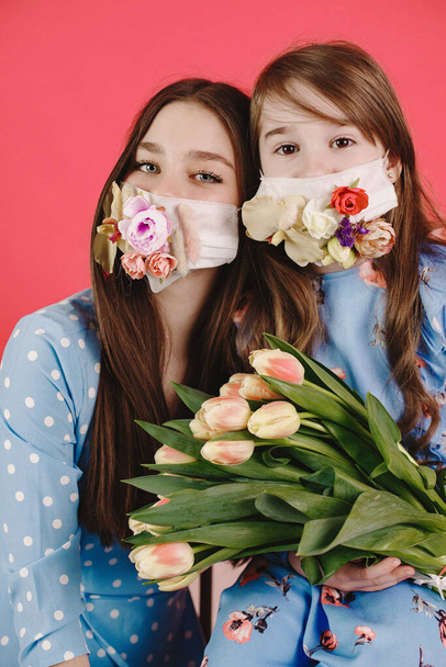 Lányok maszkban, virágokkal a vörös háttéren - Fotó, kép