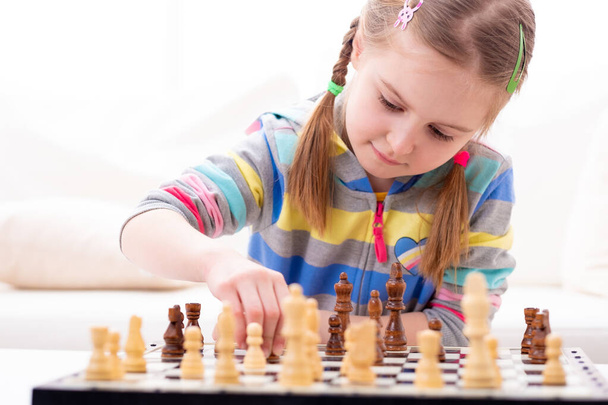 Cute little girl playing chess - Фото, изображение
