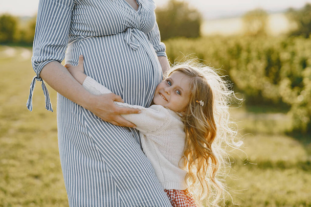 Pregnant mother with her daughter in a field - Foto, afbeelding