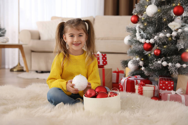 Cute little girl with box of Christmas balls at home - Photo, Image