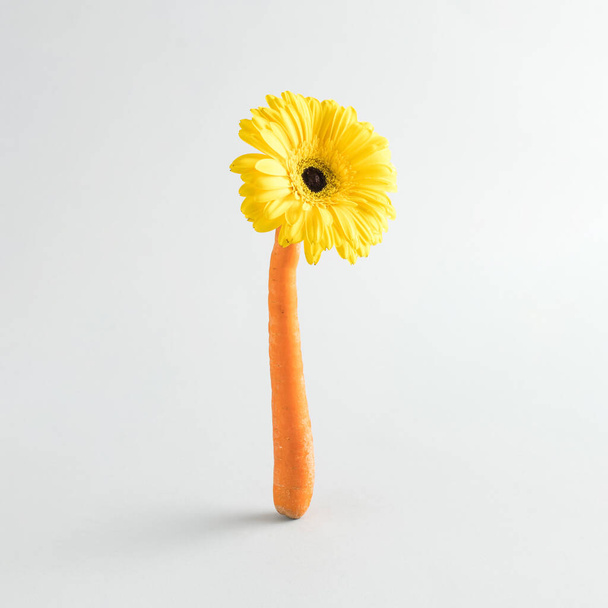 Kompozycja wielkanocna ze świeżą marchewką i kwiatami na szarym tle. Kreatywna żywność lub koncepcja wiosny - Zdjęcie, obraz