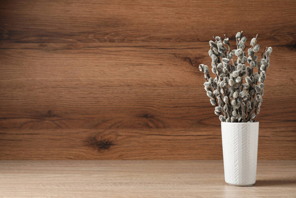 Beautiful pussy willow branches in vase on wooden table, space for text - Foto, Imagem
