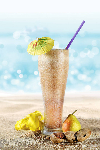 Vaso con jugo de tamarindo y pera en la arena de la playa - Photo, Image