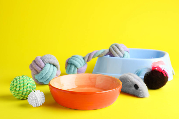 Feeding bowls and toys for pet on yellow background - Fotoğraf, Görsel