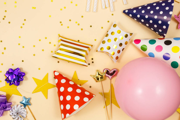Background for happy birthday celebration or party. Group of colored balloons, confetti, candles, ribbons on beige pastel background. Mock up with copy space, a place for text - Photo, Image