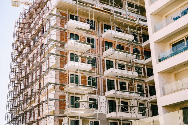 Steigers rond een modern hoogbouw gebouw in aanbouw - Foto, afbeelding