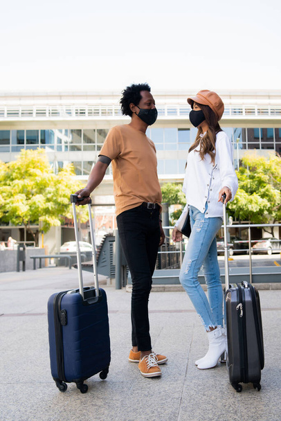 Tourist couple carrying suitcase outdoors. - Fotó, kép