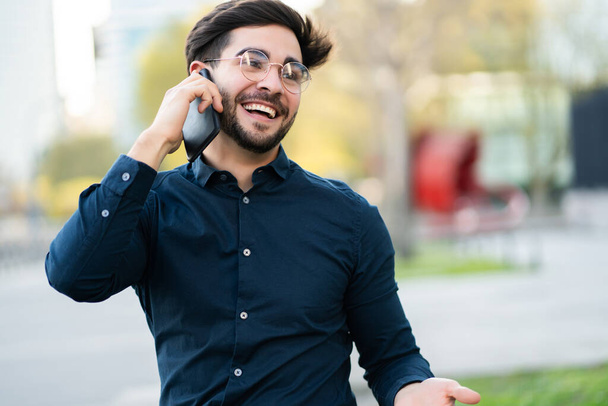Young man talking on the phone outdoors. - Φωτογραφία, εικόνα