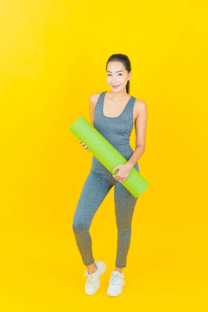 Portrait beautiful young asian woman with sportswear ready for exercise on yellow background - Foto, Imagem