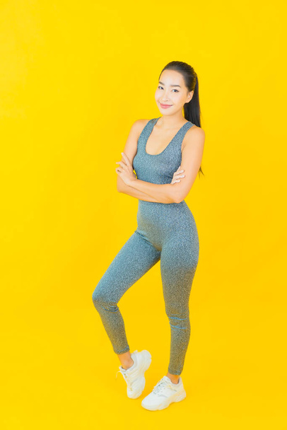 Sarı arka planda spor kıyafetleri olan güzel Asyalı kadın portresi egzersize hazır. - Fotoğraf, Görsel