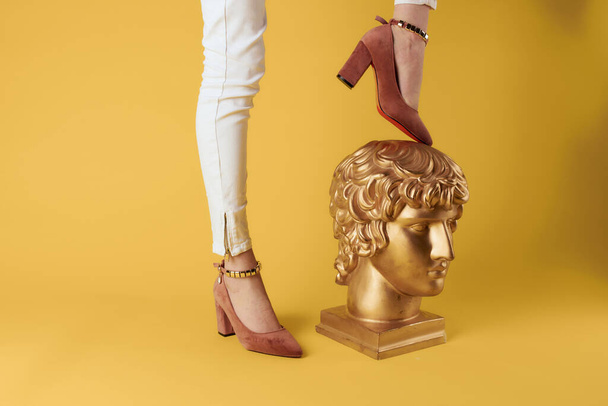 女性の足の頭の彫刻黄金の色豪華なファッション黄色の背景 - 写真・画像